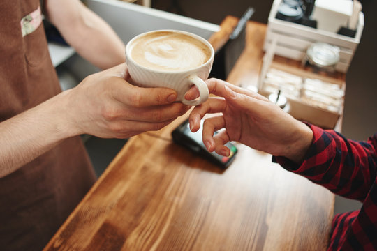 The girl picks up a coffee from a Barista. Hands and Cup closeup