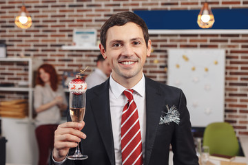 Smiling businessman holding a glass with champagne