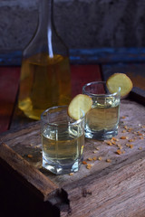 Homemade ginger tincture or ale on wooden background. Rustic style. Spice yellow liqueur in a glass. Alcohol drink.