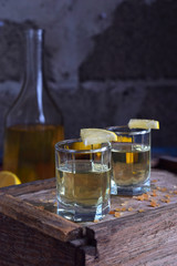 Homemade ginger tincture or ale on wooden background. Rustic style. Spice yellow liqueur in a glass. Alcohol drink.