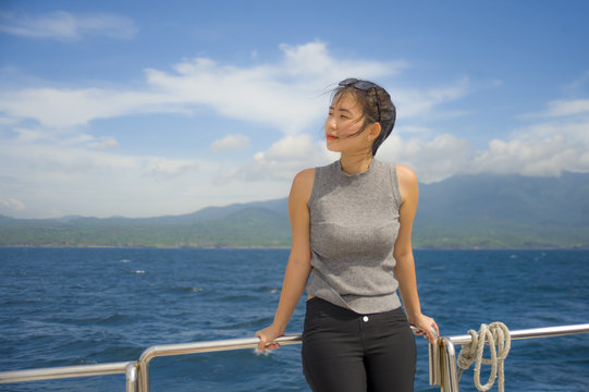young attractive and happy Asian Chinese woman on excursion ship or ferry  enjoying sea breeze on summer holiday sea boat trip