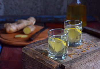 Homemade ginger tincture or ale on wooden background. Rustic style. Spice yellow liqueur in a glass. Alcohol drink.