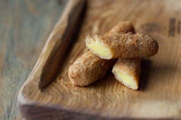 Cheese sticks deep-fried on a wooden background.