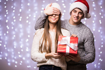 Happy young man covers with hand eyes of his women. man gives a gift on bokeh background