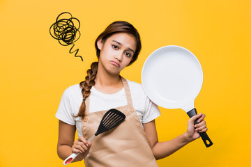 Young woman watching tablet PC while cooking.