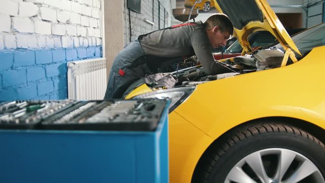 Yellow car in garage auto service - open hood - engine repairing