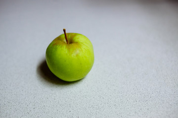 A green apple on the kitchen table.