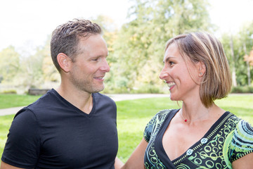 man and cute woman speak together in garden park outdoor