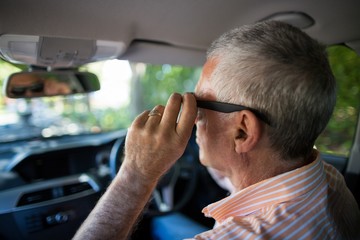 Senior man adjusting sunglasses in car