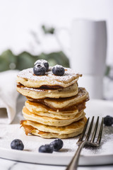 Pile of american pancakes with blueberries and powdered sugar.