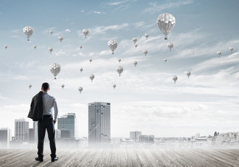 Motivation and inspiration concept with modern cityscape and businessman observing it