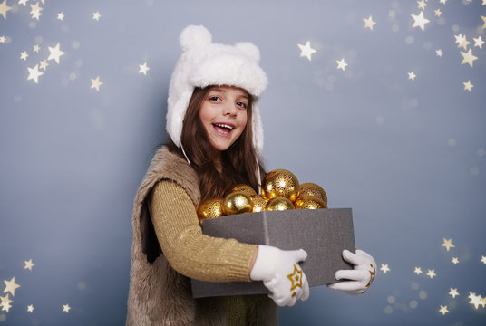 Cheerful girl holding box of christmas balls