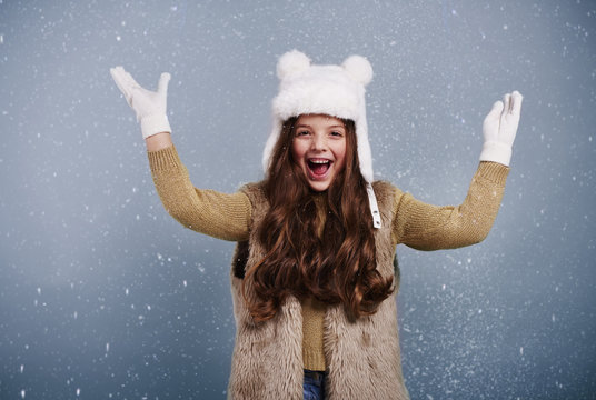 Cheerful girl among snow falling