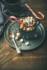Winter warming sweet drink hot chocolate with marshmallows and cocoa in mug with Christmas holiday candy cane, selective focus, copy space, vertical composition