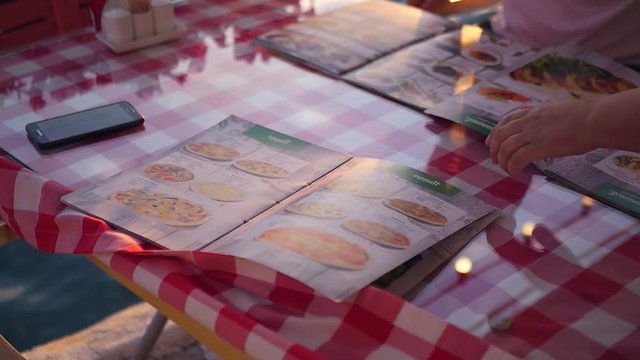 Several menus lie on the table in the restaurant, outdoors, by the water at sunset. HD, 1920x1080. slow motion.