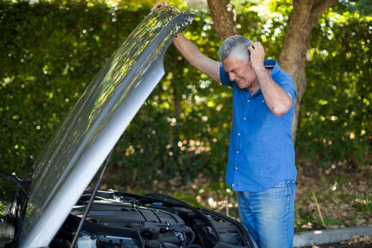 Senior Man Checking Engine Of Breakdown Car