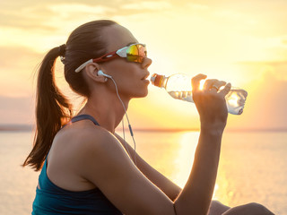 Running woman in sport sunglasses drink. Female runner with her