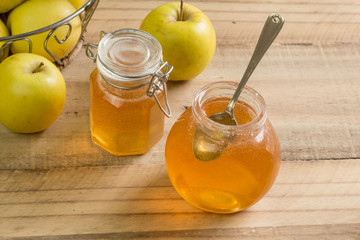 Apple jelly jam in glass jar on wooden table with apples - selective focus