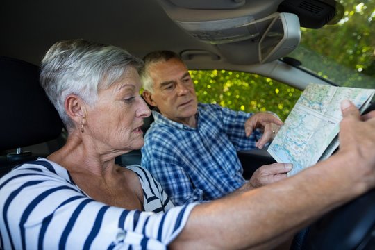 Senior couple reading map in car - Powered by Adobe