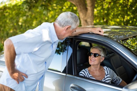 Senior Man Talking To Woman Sitting In Car