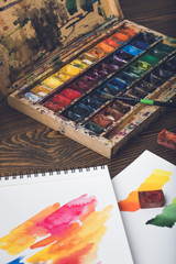 close-up view of watercolor paints, paintbrush and abstract sketches at designer workplace