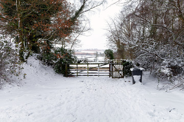 Snow covered wooden gate with winter countryside in the background