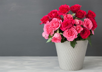 beautiful red rose flowers bouquet in vase over gray