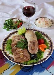 Roll of peritoneum with garlic and spices on a plate decorated with greens. The upper projection.Uzbek cuisine.