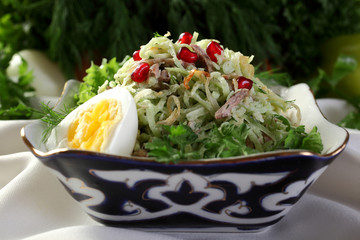 Salad with green radish with the addition of meat balls,decorated with pomegranate seeds.