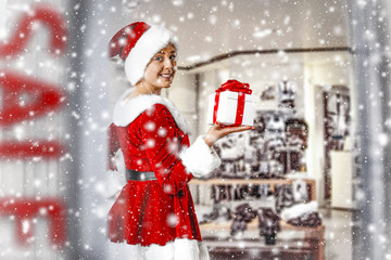 Christmas sale and woman in red dress and santa claus hat. Snow decoration and shop interior. 