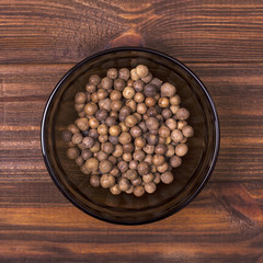 Pimento spice in a bowl on a wooden background