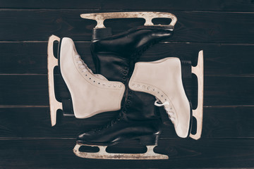 top view of pairs of white and black skates on wooden surface