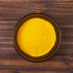 Turmeric powder in a bowl on a wooden background