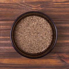 Cumin seeds in a bowl on a wooden background