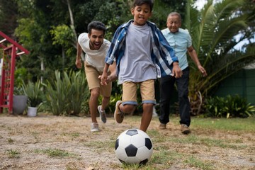 Happy family playing soccer in yard