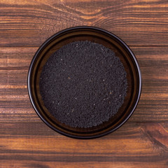 Black cumin seeds in a bowl on a wooden background