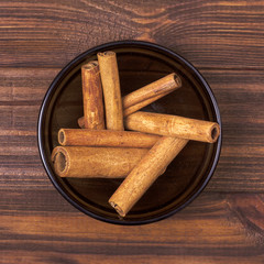 Cinnamon sticks in a bowl on a wooden background