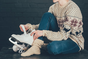 cropped image of woman sitting on gray floor and wearing white skates
