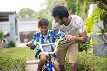 Man assisting son cycling