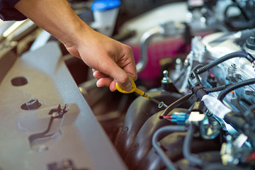 Mechanic checking engine oil in auto repair shop
