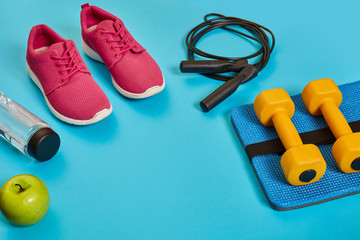 Flat lay of dumbbell, bottle of water, jump rope and sneaker, sport equipments, fitness items, top view