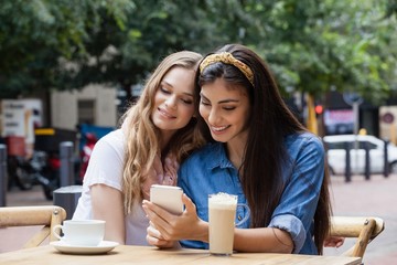 Friends using mobile phone while sitting on chairs