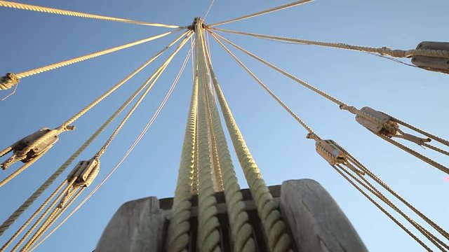 A sailboat mast seen from below, ropes and tackle of old ship