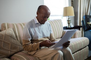 Senior man using phone while holding document