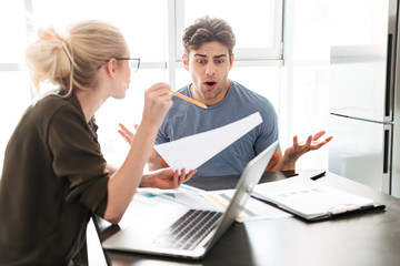 Young busy man has a quarrel with his woman while working at home