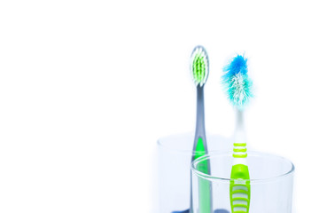 New toothbrush and old toothbrush (damaged) in clear glass for teeth cleaning isolated on white background - concept 