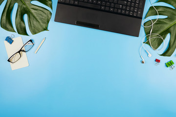 Beautiful flatlay with a laptop, glasses, philodendron leaves and other business accessories....