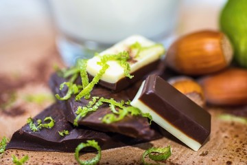 Pieces of chocolate, lime bark, hazelnut and glass of milk.