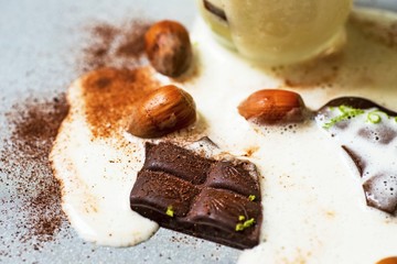Broken chocolate and hazelnut in spilled milk.