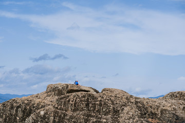 Female and man on the edge of the rock look on the monasteries of Meteora. Meteora in Greece in...